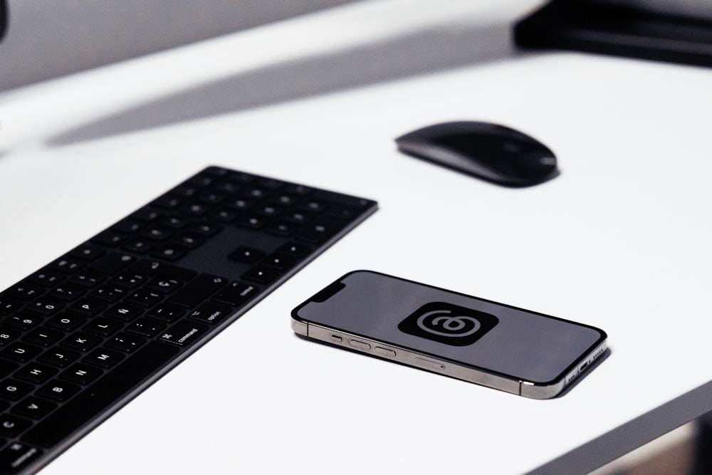 a keyboard, mouse, and cell phone sitting on a desk