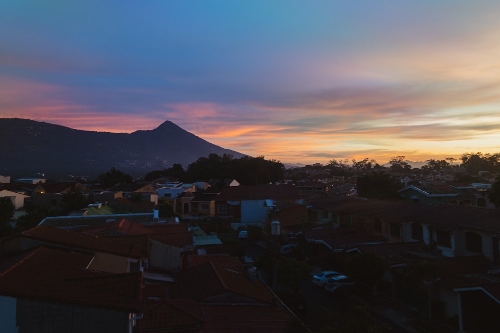 uma vista do pôr do sol de uma cidade com uma montanha ao fundo