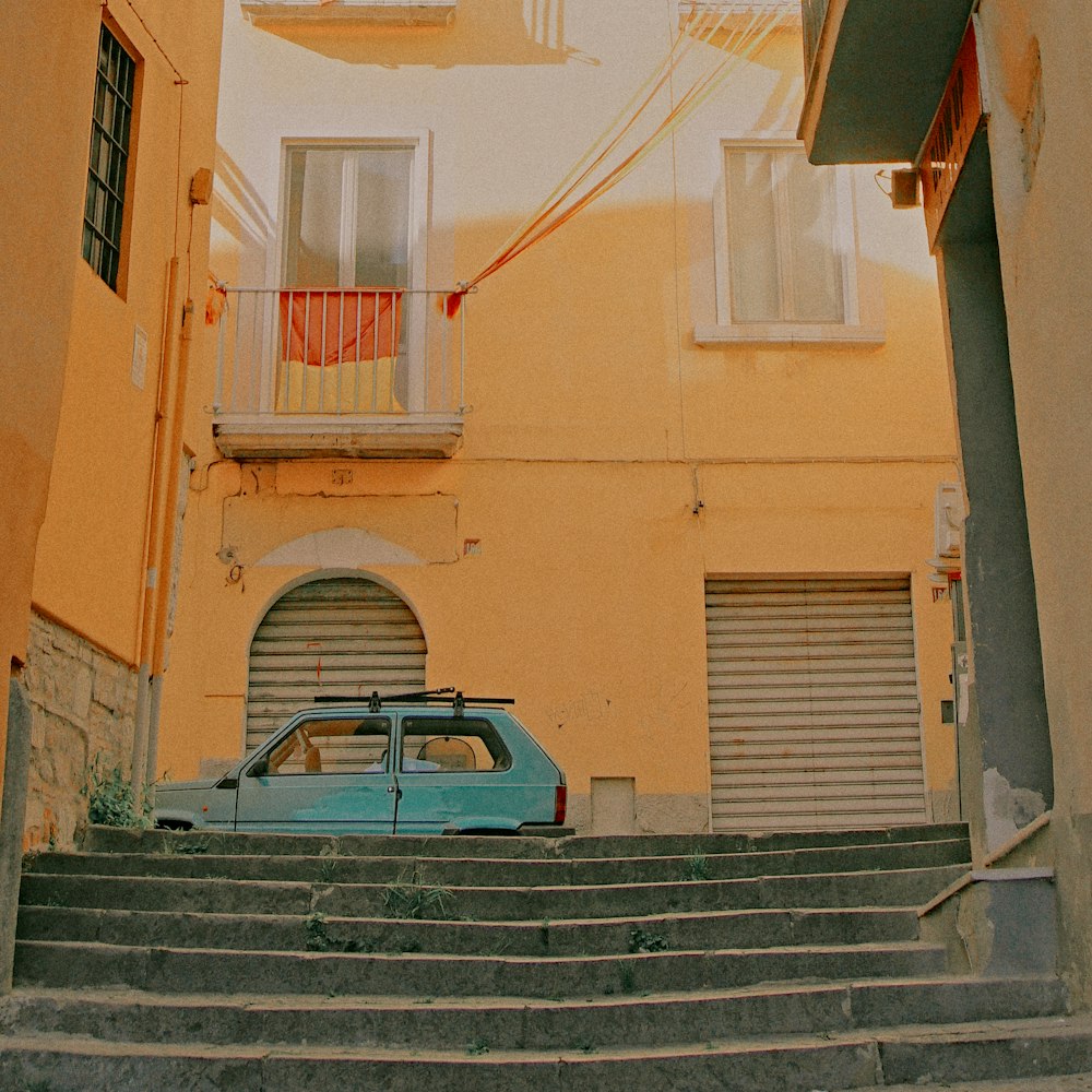 a blue car parked in front of a yellow building