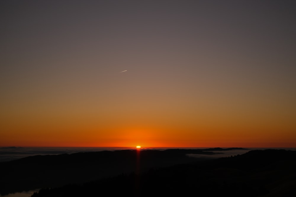 the sun is setting over a mountain range