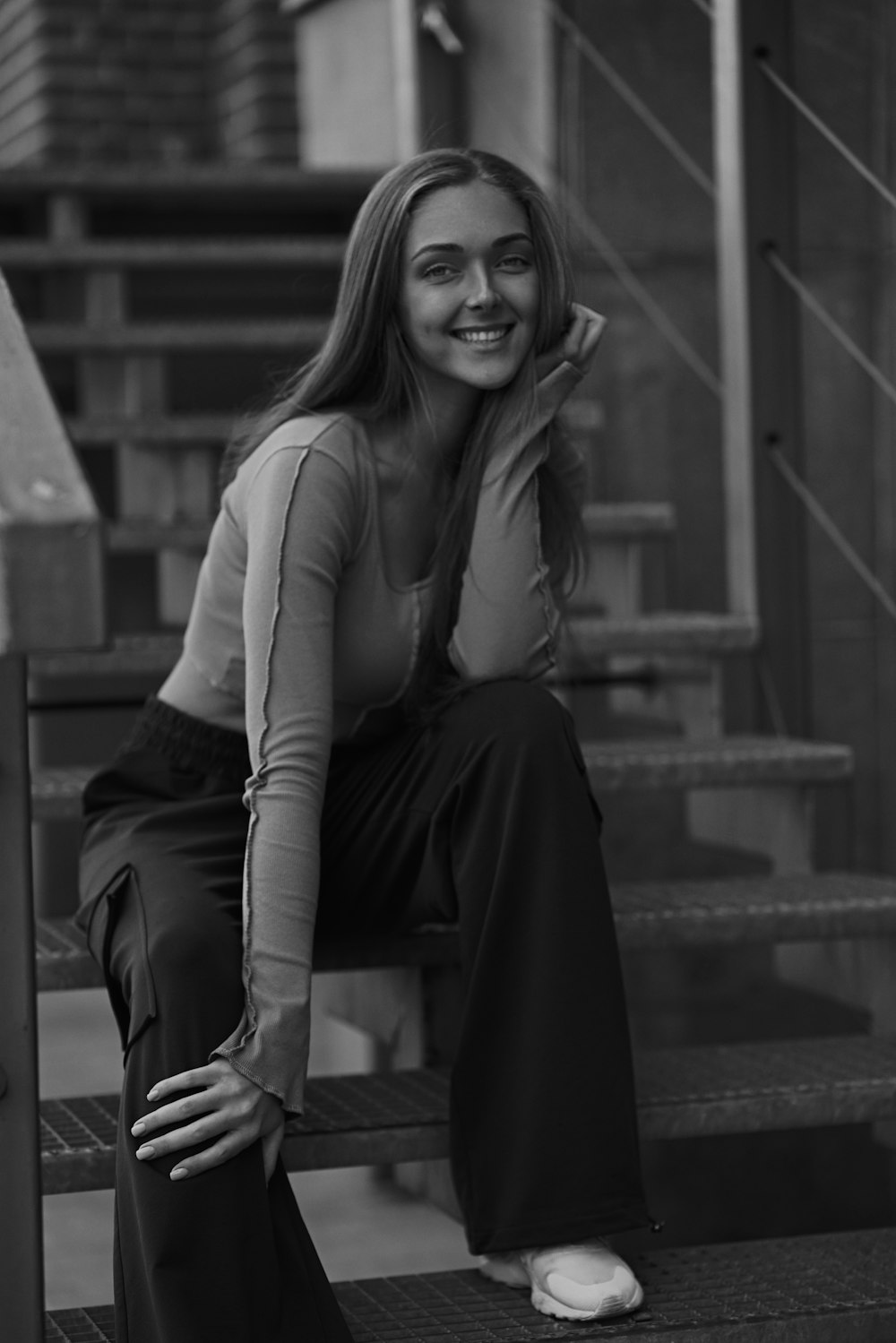 a black and white photo of a woman sitting on stairs