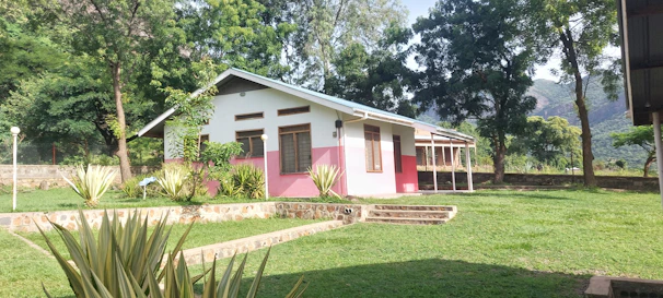 A cute pastel-colored Minecraft house with a garden and trees around it.