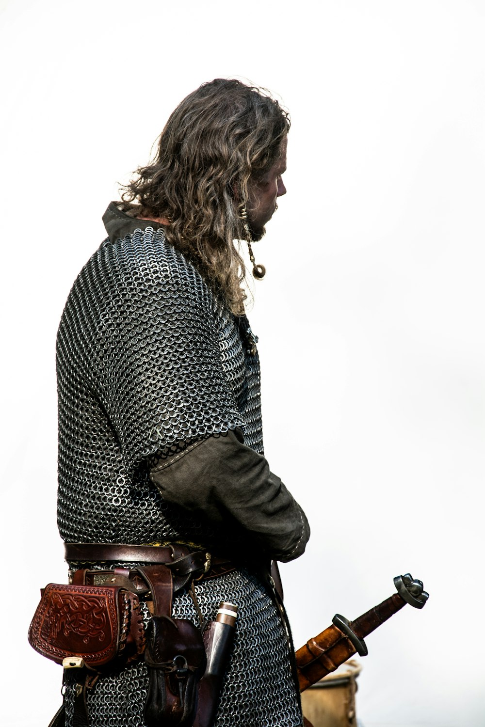 a man with long hair wearing a chain mail and holding a sword