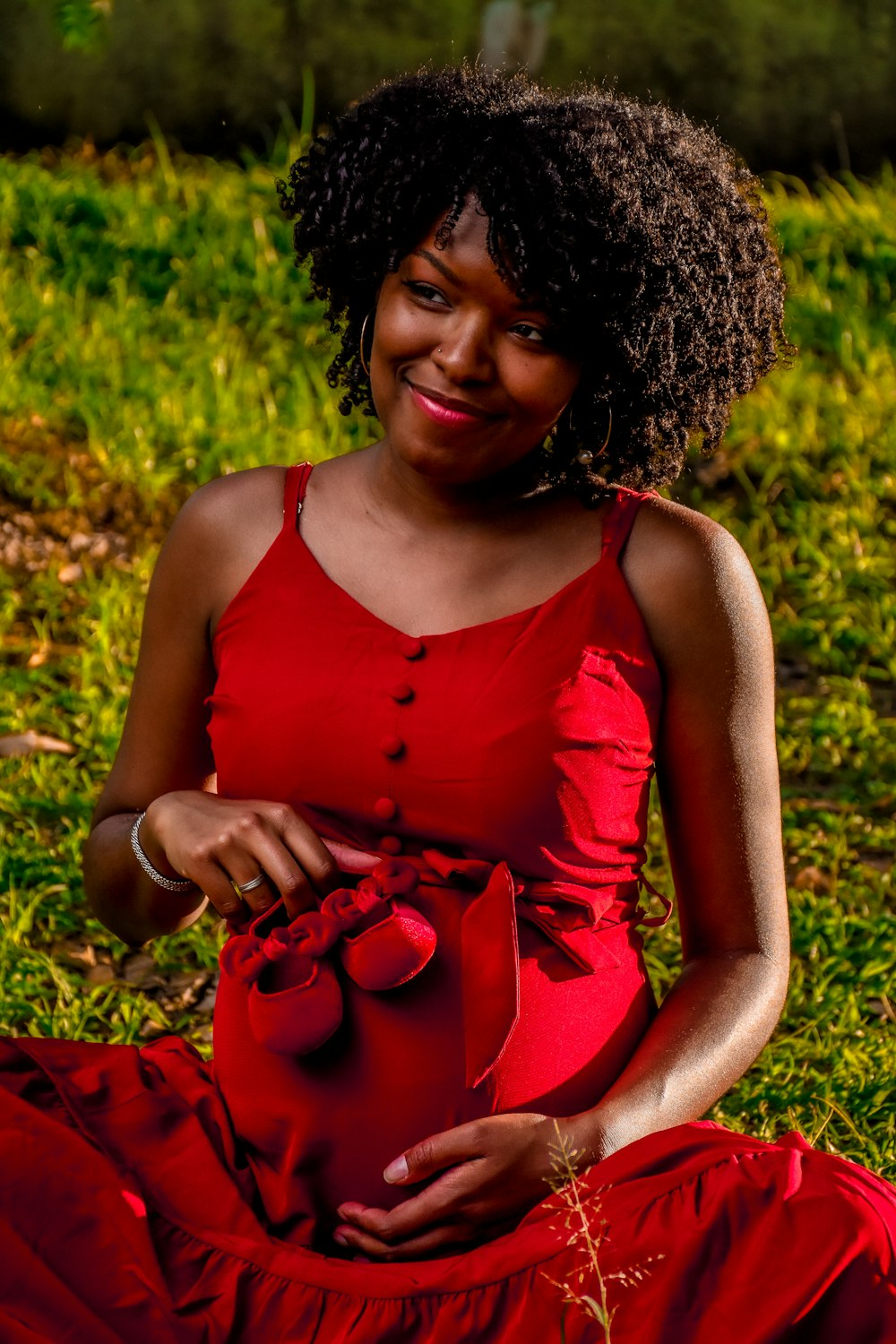 a woman in a red dress sitting on the grass