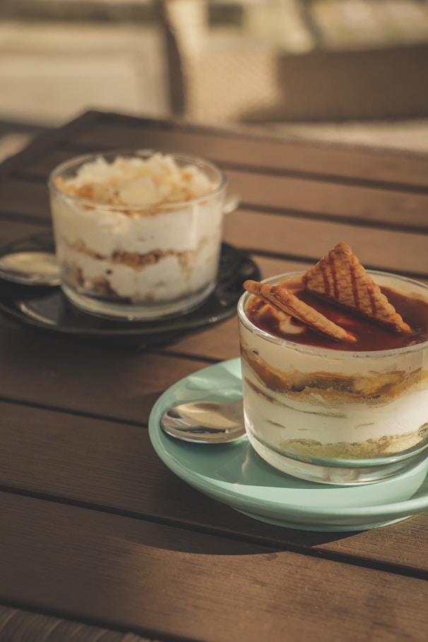 two desserts are sitting on a wooden table