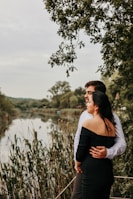 Couple enjoying a peaceful riverside picnic surrounded by greenery.
