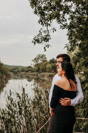 Couple enjoying a peaceful moment by the riverbank surrounded by lush greenery and ancestral petroglyph symbols.