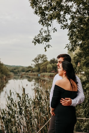 Couple enjoying a peaceful riverside picnic surrounded by greenery.