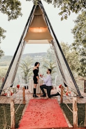 a man and woman sitting at a table in front of a tent