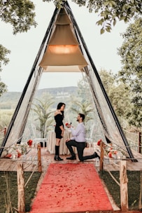 a man and woman sitting at a table in front of a tent