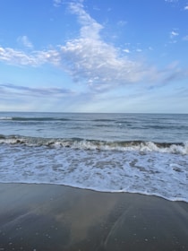 Close-up of a serene beach with soft waves under a bright blue sky.