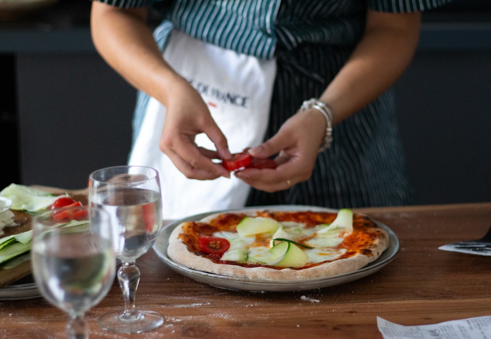 a woman is putting toppings on a pizza