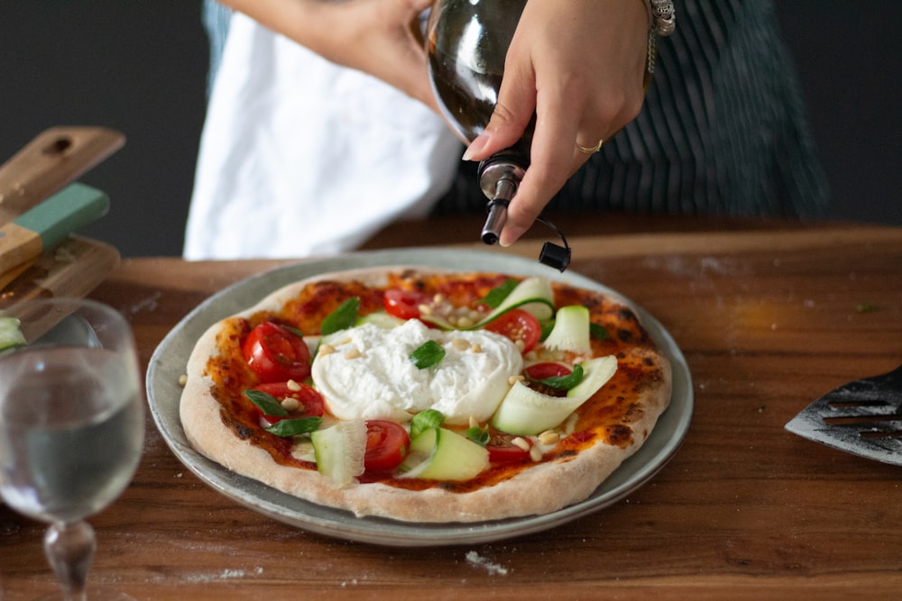 a person is putting cheese on a pizza