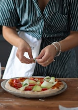 A chef preparing a pizza in a vibrant kitchen, showcasing fresh ingredients and culinary skills.