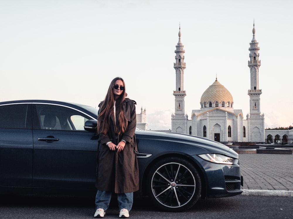 a woman standing next to a car in front of a building