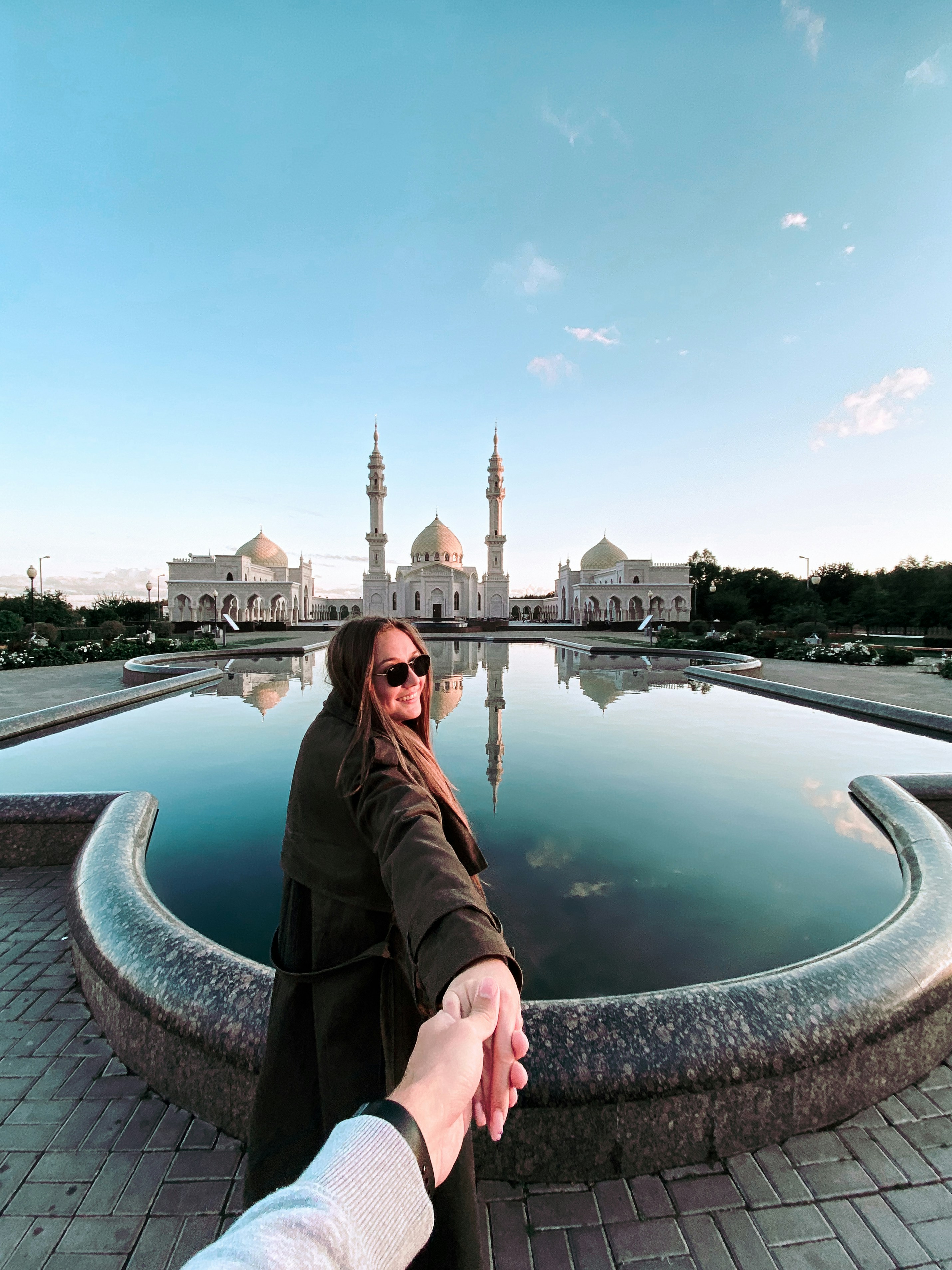 a woman holding the hand of a man in front of a fountain
