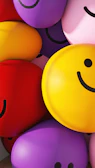 Close-up of a happy face with colorful balloons in the background.