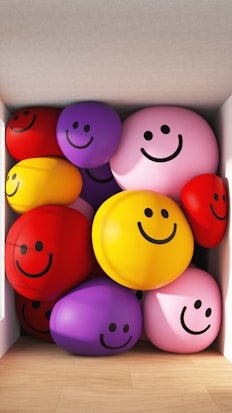 A collection of colorful, inflated spheres with smiling faces fills a corner of a room, casting soft shadows on the wooden floor.