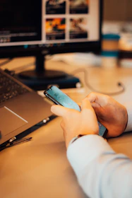 a person sitting at a desk using a cell phone