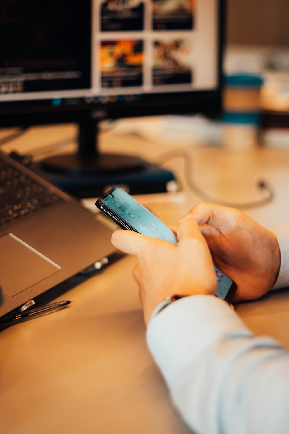 a person sitting at a desk using a cell phone