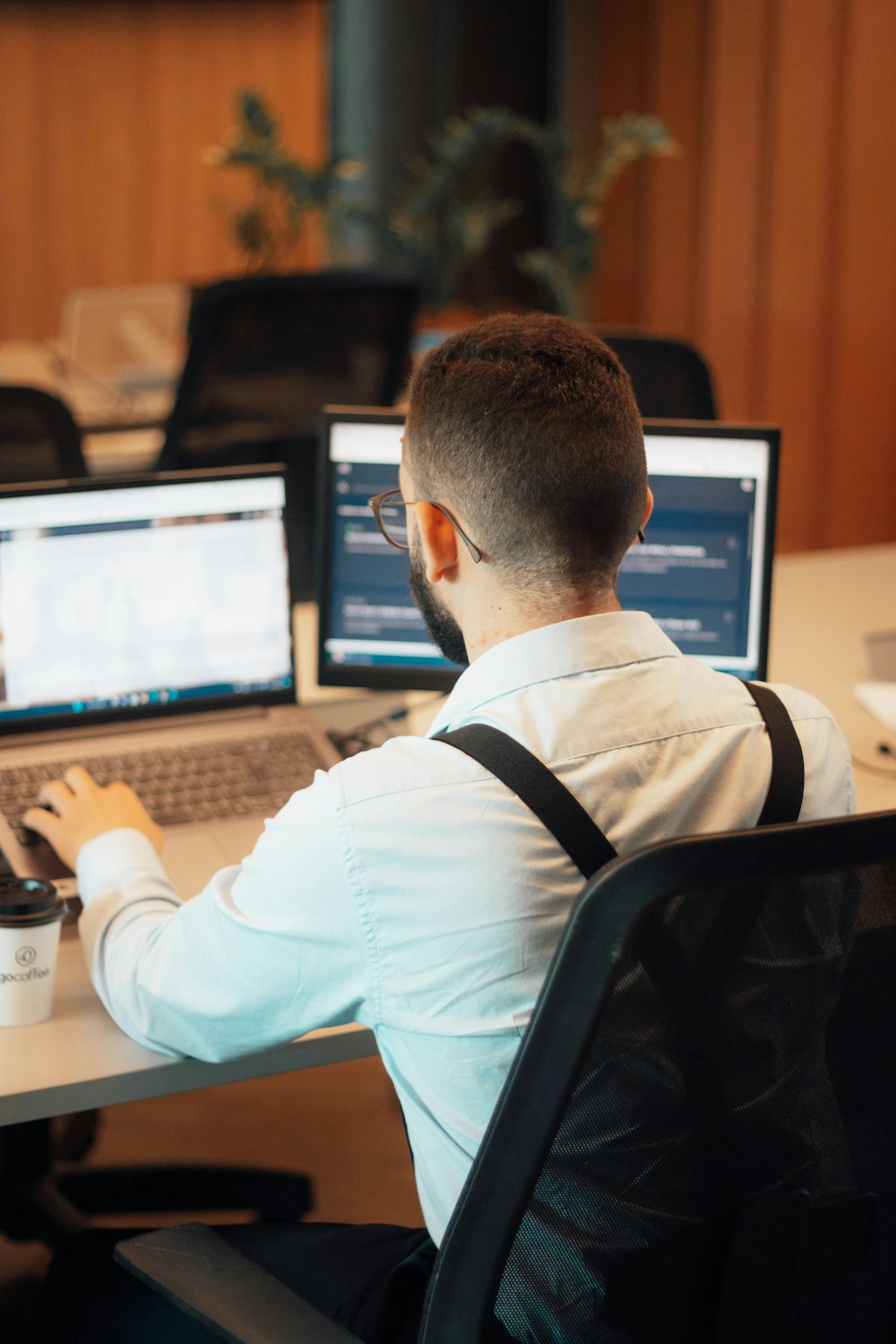 a man sitting at a desk with two laptops