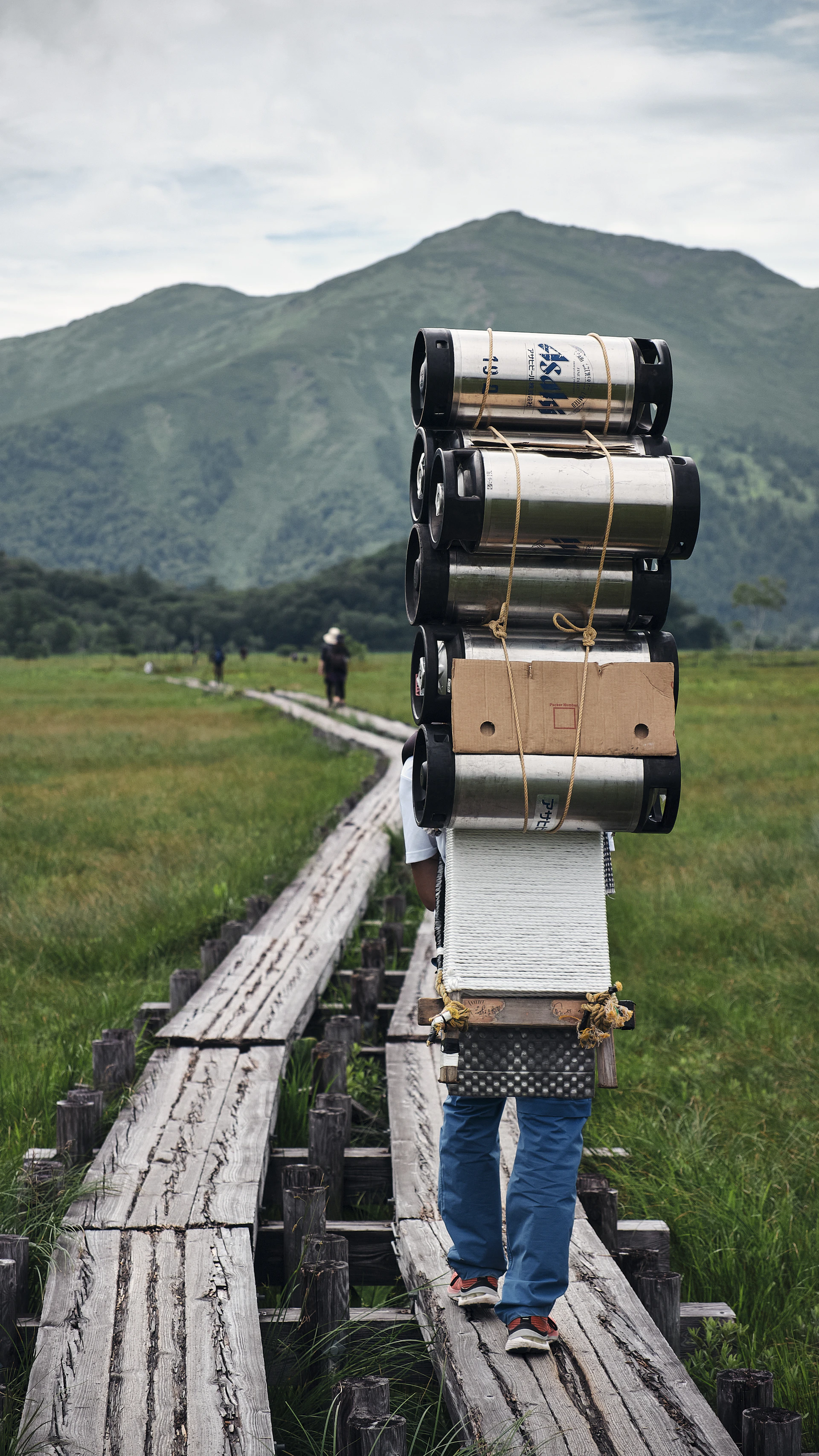 a person carrying a stack of luggage on a train track