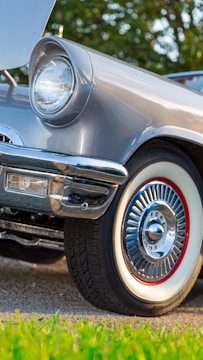 Close-up of a classic car being carefully examined outdoors.
