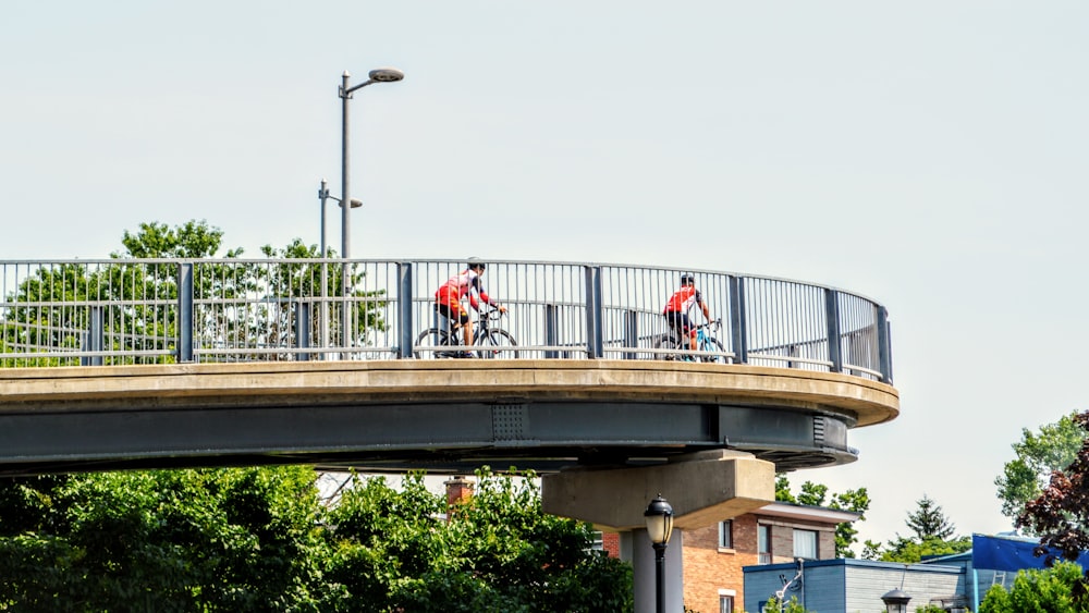 a couple of people riding bikes across a bridge