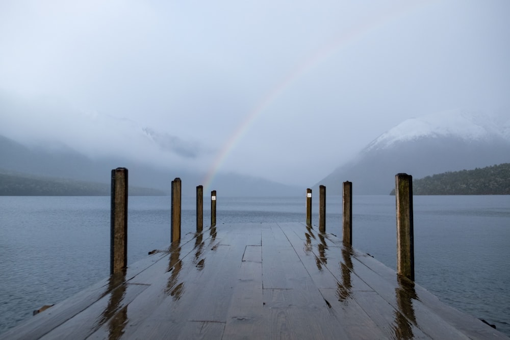 a wooden dock with a rainbow in the background