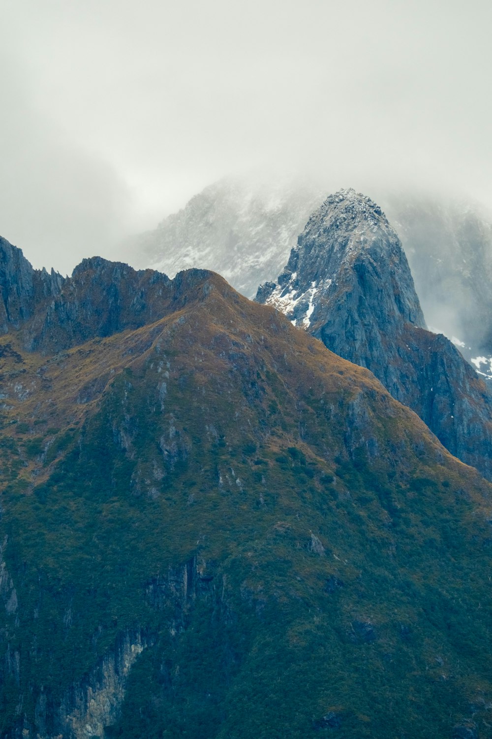 a very tall mountain covered in snow and clouds