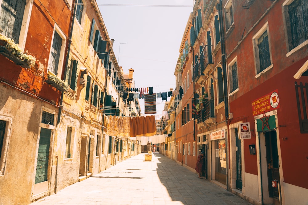 a narrow city street with buildings and a laundry line