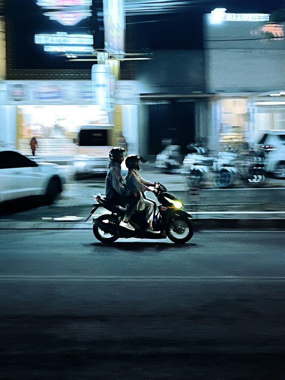 two people riding a motorcycle on a city street