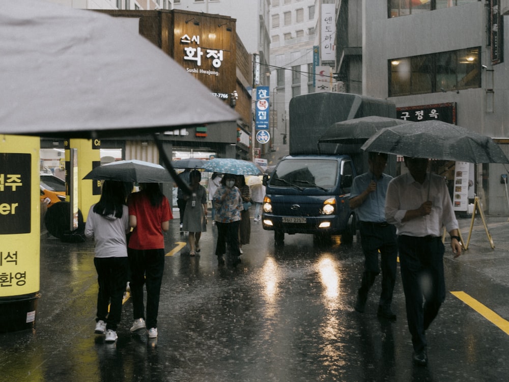 um grupo de pessoas caminhando por uma rua segurando guarda-chuvas