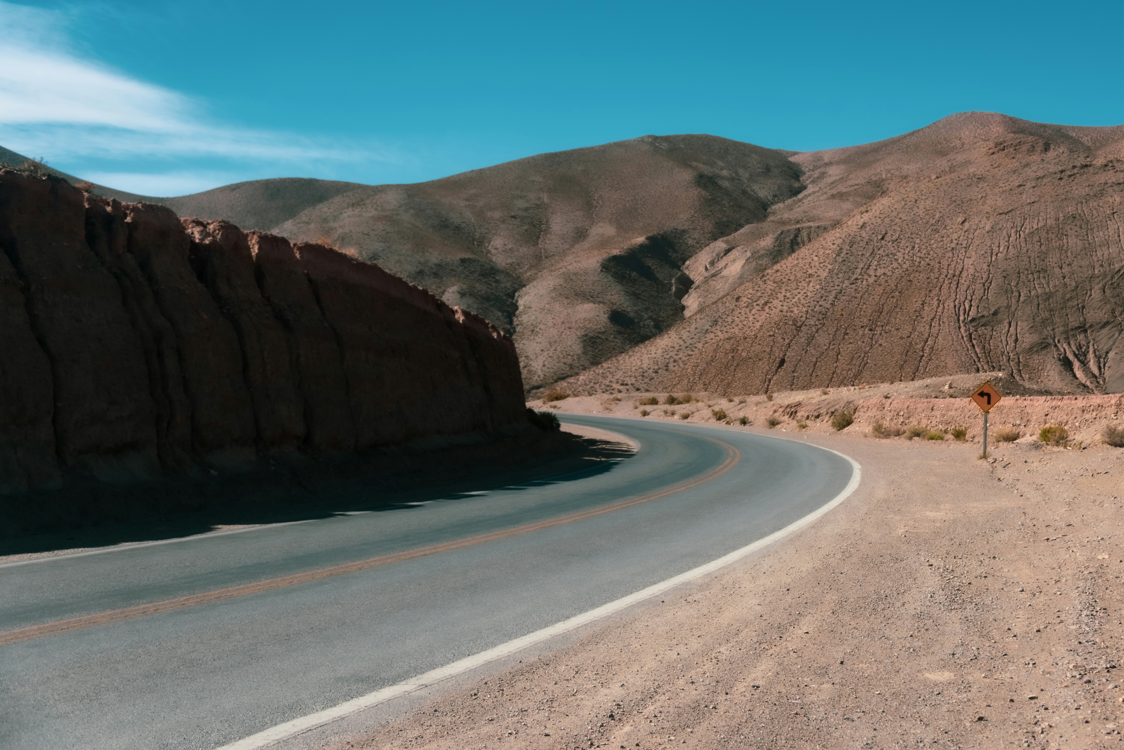 a road in the middle of a desert with mountains in the background, A curvy road in Northern Argentina, winding through the scenic landscape