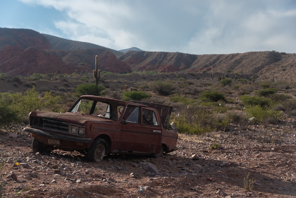 an old truck sitting in the middle of a desert