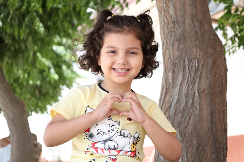 a little girl making a heart with her hands