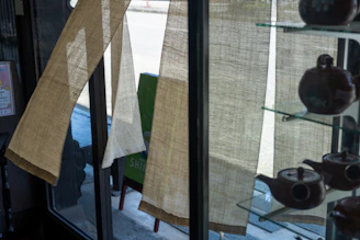 A cozy display of elegant tea sets arranged on a wooden shelf with soft natural lighting.