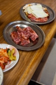 A rustic wooden table filled with various cuts of grilled meats and side dishes.