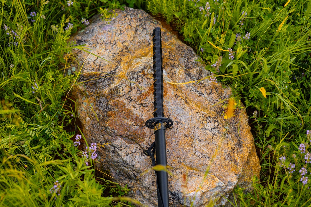 a sword laying on top of a rock in the grass