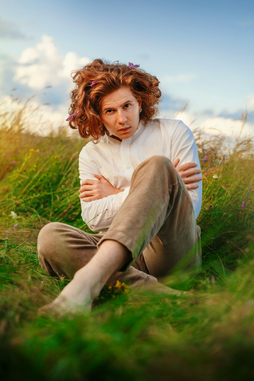 a woman with red hair sitting in a field