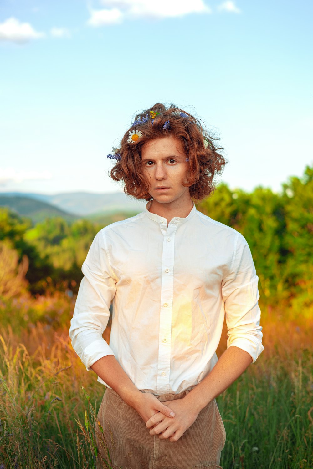 a man standing in a field with his hands in his pockets