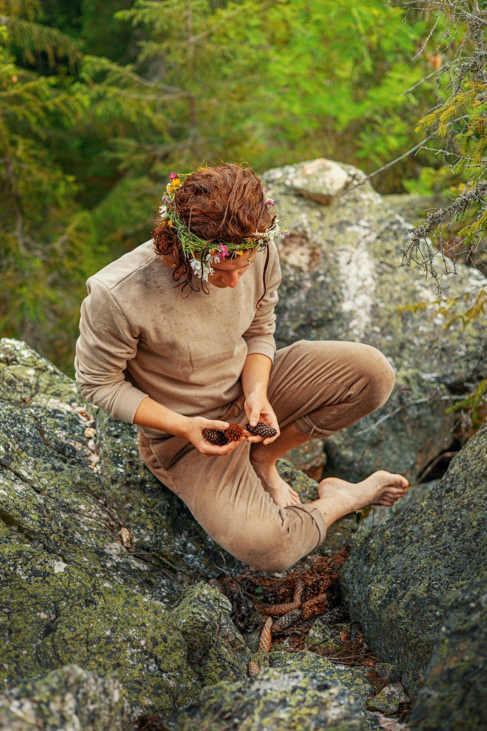 a woman sitting on top of a rock next to a forest