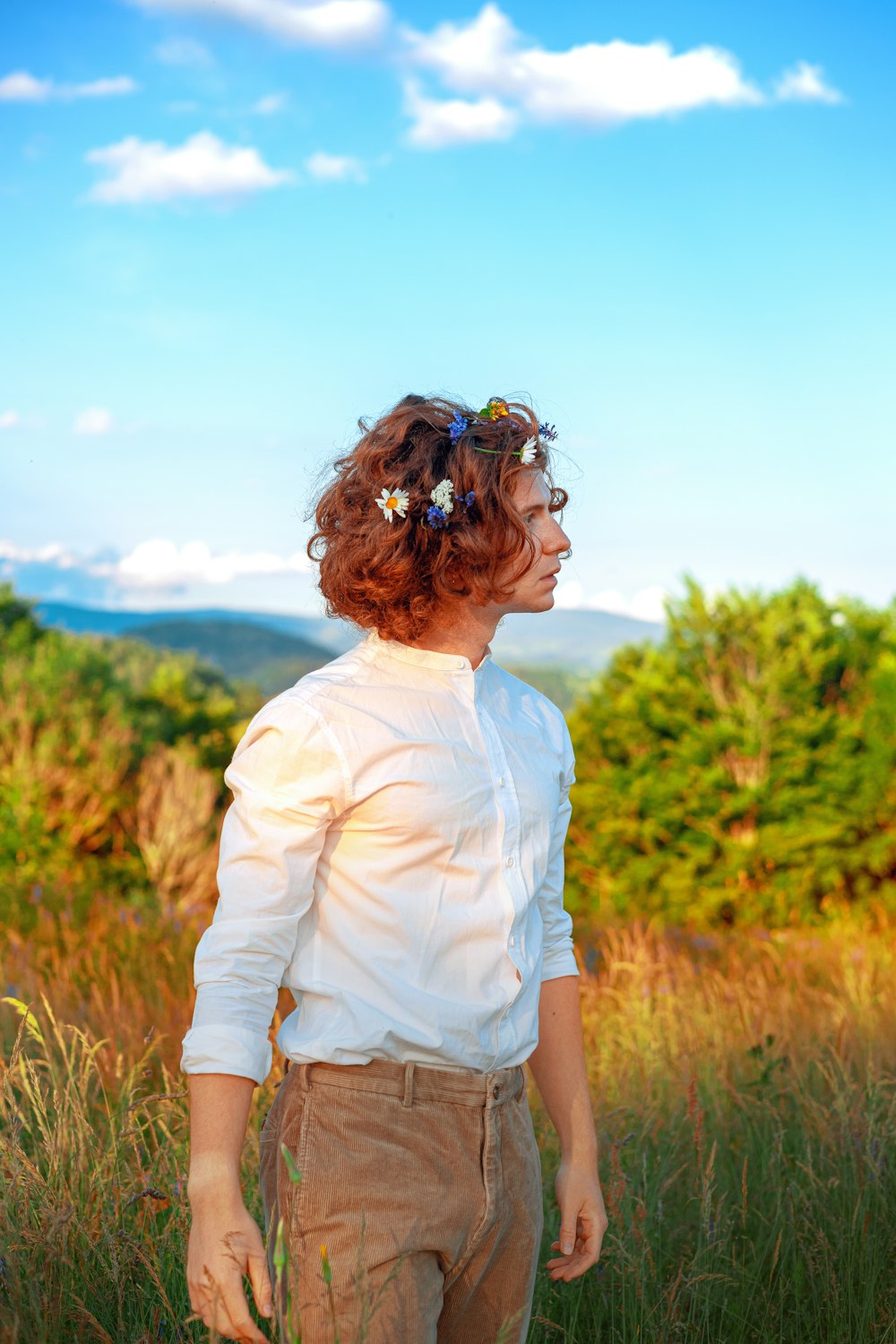 a man standing in a field with a flower in his hair