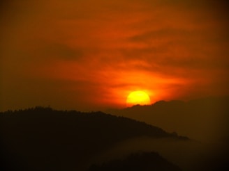 A warm glowing sun setting behind distant mountains, casting golden light.