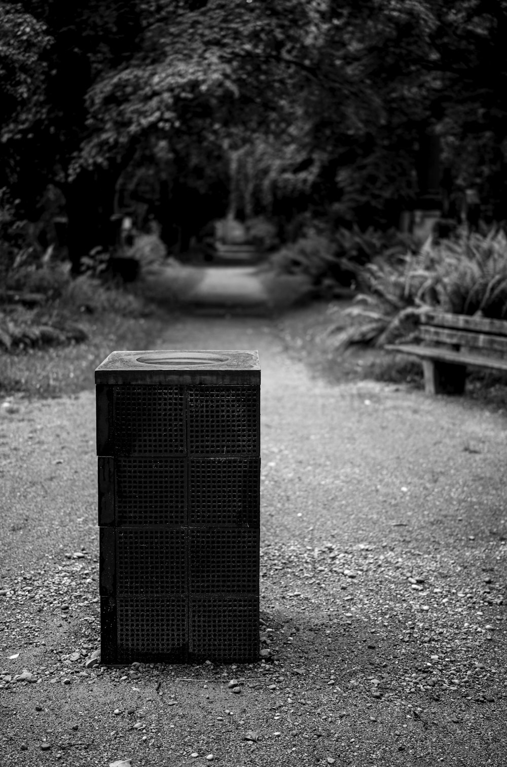 a trash can sitting in the middle of a dirt road