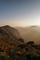 Golden sunlight spilling over desert hills with towering snowcapped mountains behind.