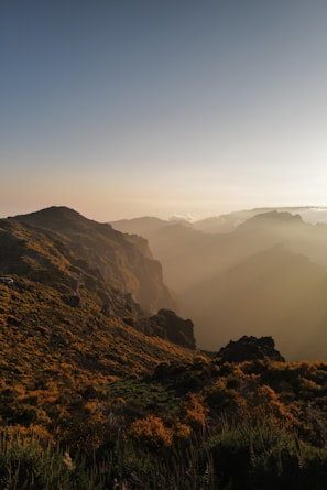 Golden sunlight spilling over desert hills with towering snowcapped mountains behind.
