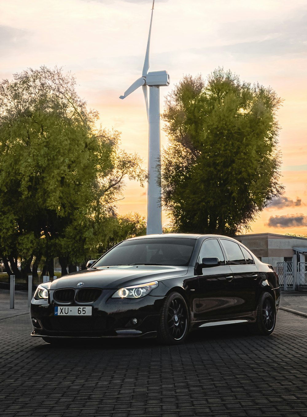 a black car parked in front of a wind turbine