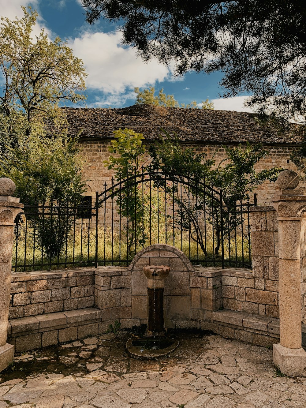 a stone building with a gate and a fountain