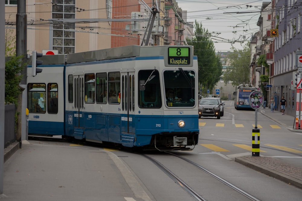 a blue and white train traveling down a street